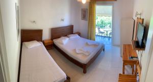 a bedroom with two beds and a television and a balcony at Filoxenia Kontogiannis in Lazaráta
