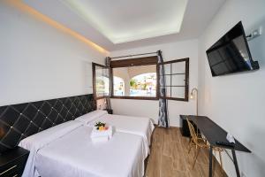 a hotel room with two beds and a flat screen tv at Hotel Bajamar Ancladero Playa in Nerja