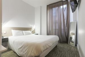 a bedroom with a large white bed and a window at Hotel du Clocher in Rodez