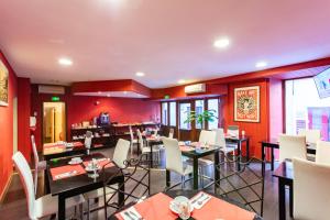 a dining room with tables and white chairs at Hotel du Clocher in Rodez