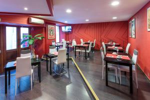 a restaurant with tables and chairs and red walls at Hotel du Clocher in Rodez