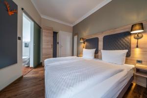 - une chambre avec un grand lit blanc et une grande fenêtre dans l'établissement Hotel Hirsch, à Kehl