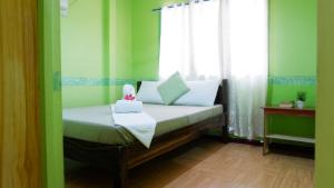 uma pequena cama num quarto com uma janela em Mountain Side Inn em El Nido