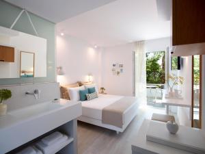 een witte slaapkamer met een bed en een badkamer bij Kouros Seasight Hotel in Pythagoreio