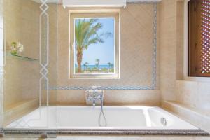 a bathroom with a bath tub with a window at Kempinski Hotel Soma Bay in Hurghada