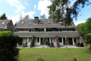 una casa con sillas y mesas delante de ella en Vakantiepark de Bosrand, en Vaassen