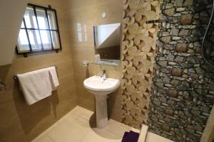 a bathroom with a sink and a stone wall at Le Ronce Villa in Anse Royale