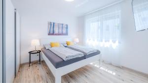 ein weißes Schlafzimmer mit einem Bett und einem Fenster in der Unterkunft Apartments Jesse in Sankt Kanzian am Klopeiner See