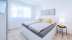 una camera da letto bianca con un letto con cuscini gialli di Apartments Jesse a Sankt Kanzian