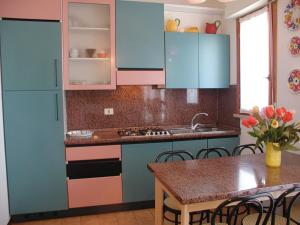 a kitchen with blue cabinets and a table at Appartamenti Valbella con piscina in Bibione