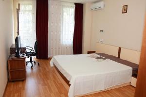 a bedroom with a bed and a television in it at Апартамент София in Golden Sands