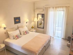 - une chambre avec un grand lit blanc et une fenêtre dans l'établissement NIKOLETA'S CORFU APARTMENTS, à Gouviá
