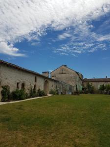 a building with a grass yard and a cloudy sky at Les Hauts De Chalonne in Le Gond-Pontouvre