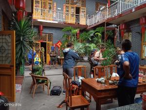 un groupe de personnes debout dans une pièce avec des tables et des chaises dans l'établissement Pingyao Jiaxin Guesthouse, à Pingyao