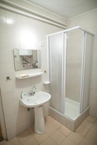 ein weißes Bad mit einer Dusche und einem Waschbecken in der Unterkunft Tusculanum Panzió in Mindszentkálla