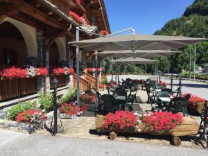a patio with tables and chairs with flowers and an umbrella at B&B San Sebastiano in Vernante