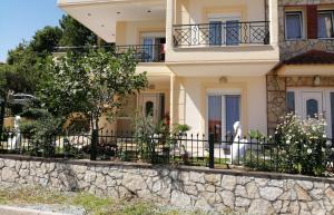 a house with a fence and a stone wall at Swan's garden olympus luxury apartment in Litochoro