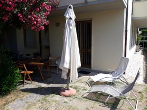 una sombrilla blanca, 2 sillas y una mesa en NOVITA'!! Intero appartamento a Marina di Cecina en Marina di Cecina