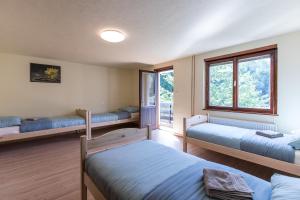 a bedroom with three beds and two windows at Dolar Guesthouse Bled in Bled