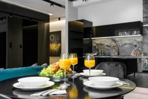 una mesa con un plato de comida y dos vasos de zumo de naranja en ZLOTA Luxury Apartments en Varsovia