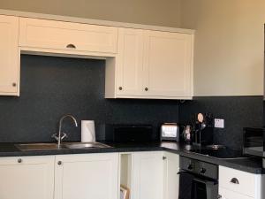科克茅斯Dovenby Apartment- great base for exploring Lake District的带白色橱柜和水槽的厨房