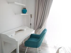 a white desk with a blue chair next to a window at Aquamarine in Oroklini