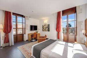 Grande Albergo Alfeo في سيراكوزا: غرفة نوم بسرير ومكتب ونوافذ