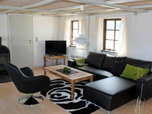 ホにあるThree-Bedroom Holiday home in Blåvand 42のリビングルーム(黒いソファ、テーブル付)