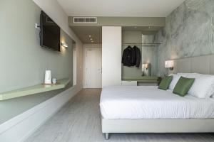 a bedroom with a large white bed with green pillows at Hotel Amburgo in Bibione