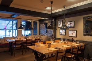 un ristorante con tavoli e sedie in legno e finestre di Hotel Provisorium13 a Arosa