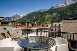 einen Tisch und Stühle auf einem Balkon mit Bergblick in der Unterkunft Penthouse le Bartavel - Chamonix All Year in Chamonix-Mont-Blanc