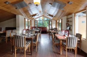un restaurante con mesas y sillas de madera y ventanas en Hotel Greenfields, en Manali