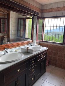 un bagno con due lavandini e un grande specchio di Cortijo la Dehesa del Trabuco a Villanueva del Trabuco
