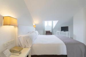 a bedroom with a white bed and a desk and a television at Hotel Suances in Suances