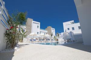 a pool with chairs and umbrellas next to a building at Fig Tree Bay Residences Lantiana Villa 1 in Protaras