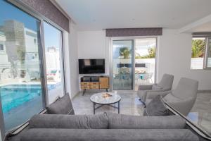 a living room with a couch and chairs and a tv at Fig Tree Bay Residences Lantiana Villa 1 in Protaras