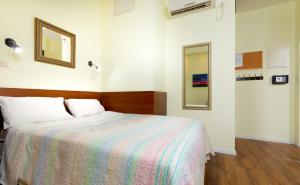 a bedroom with a bed with a colorful blanket and a mirror at Pina Ba'Moshava in Haifa