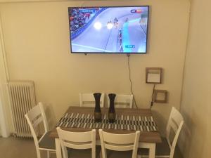 einen Tisch mit Stühlen und einen TV an der Wand in der Unterkunft Thiseio Big Apartment in Athen