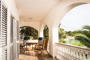 een veranda met een tafel en stoelen en uitzicht op het water bij La Villa-Silba in Silba