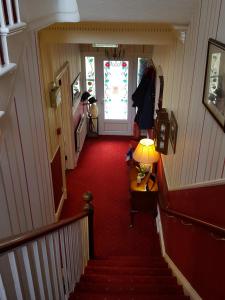 a hallway with a red carpet and a door with a lamp at Dorchester House in Keswick