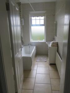 a bathroom with a tub and a sink and a window at Meadowville Self-Catering in Cushendall