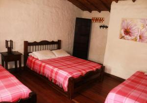 1 dormitorio con 1 cama con manta roja y blanca en Hostal El Zafiro Del Café, en El Mesón