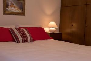 um quarto com uma cama com almofadas vermelhas e um candeeiro em AUGUSTA casa vacanza em La Thuile
