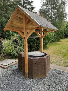 een houten paviljoen met een dak boven een bakstenen gebouw bij Ferienwohnung Wichtelgarten in Kranenburg