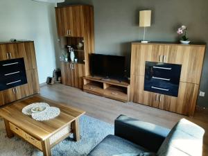 a living room with wooden furniture and a tv at Ferienwohnung Wichtelgarten in Kranenburg
