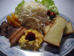 ein Teller mit Eiern, Käse, Brot und Gemüse in der Unterkunft Valentine (Adult Only) in Tottori