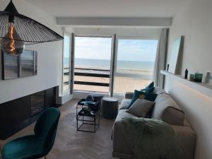 een woonkamer met een bank en uitzicht op het strand bij Seashore Beach View in Koksijde
