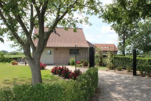 une maison avec un arbre et des fleurs dans la cour dans l'établissement 't Ligt ter Velde, oase van rust, sauna, directie Brugge, à Lichtervelde