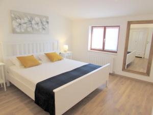 um quarto com uma grande cama branca e um espelho em Lupetina em Krnica