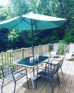 a table and chairs with an umbrella on a deck at The Retreat in Pett